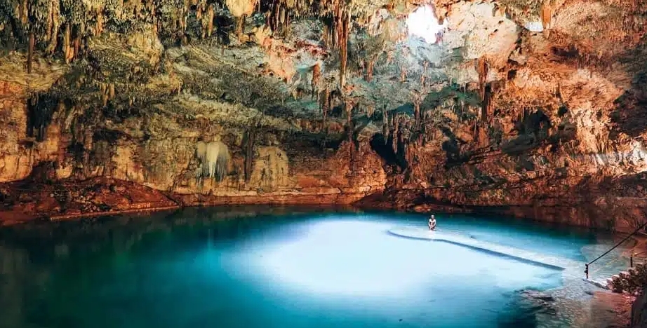 How to Get to Cenote Suytun: Discover the Easiest Way to Reach Yucatán’s Most Magical Cenote cenote suytun 6 Photographer capturing famous stalactite silhouette and natural light beam in Cenote Suytun